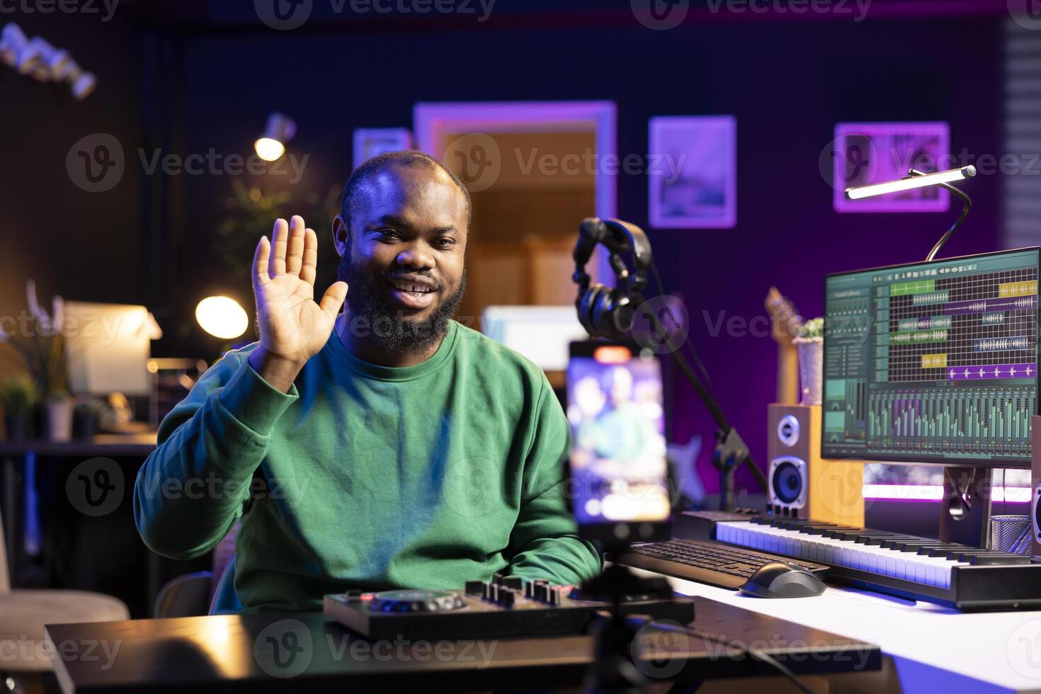 Skilled audio engineer teaching online mixing tunes lessons by using a smartphone on tripod to record himself in home studio. Producer hosting a master class with soundboard console gear. photo