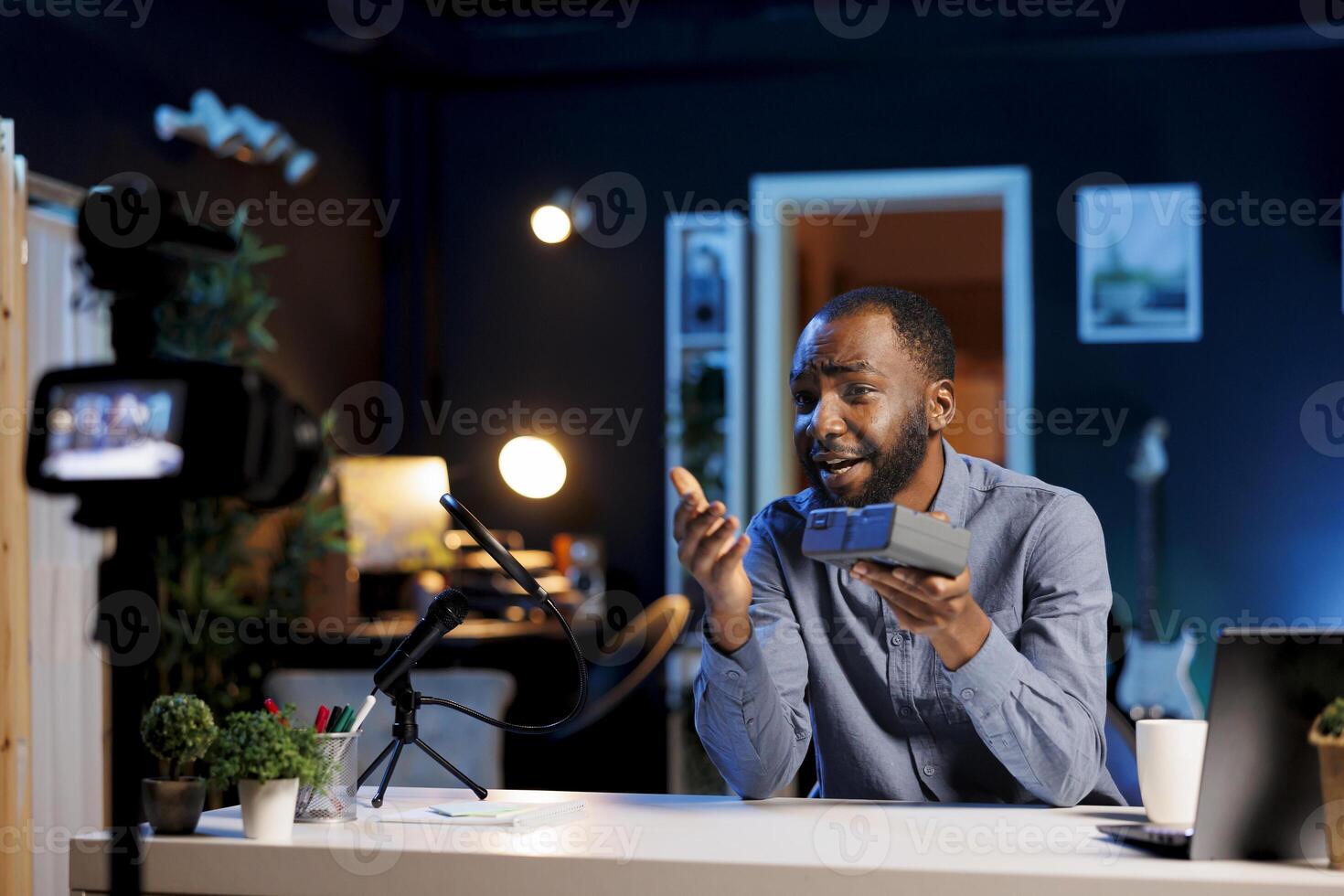 Tech guru excited to review newly released V mount battery, comparing voltage power with older models. Technology expert filming online , analyzing rechargeable professional lithium accumulator photo