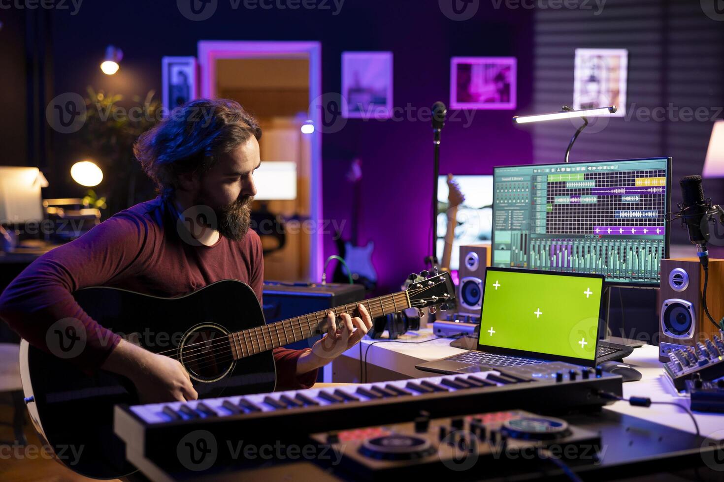 Artist songwriter playing guitar by watching online musical lessons on laptop with greenscreen, learning to play acoustic instrument in home studio. Musician singing to record tunes. photo