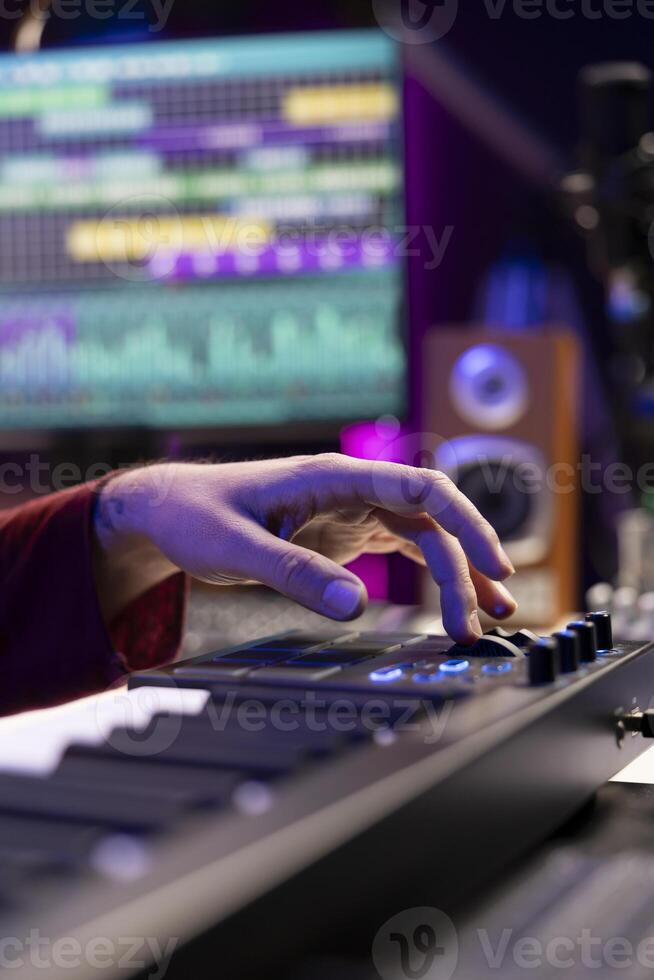 Audio engineer mixing and mastering music on daw software interface, creating cool modern tunes with acoustics and equalizer. Artist recording songs on soundboard panel in his home studio. photo