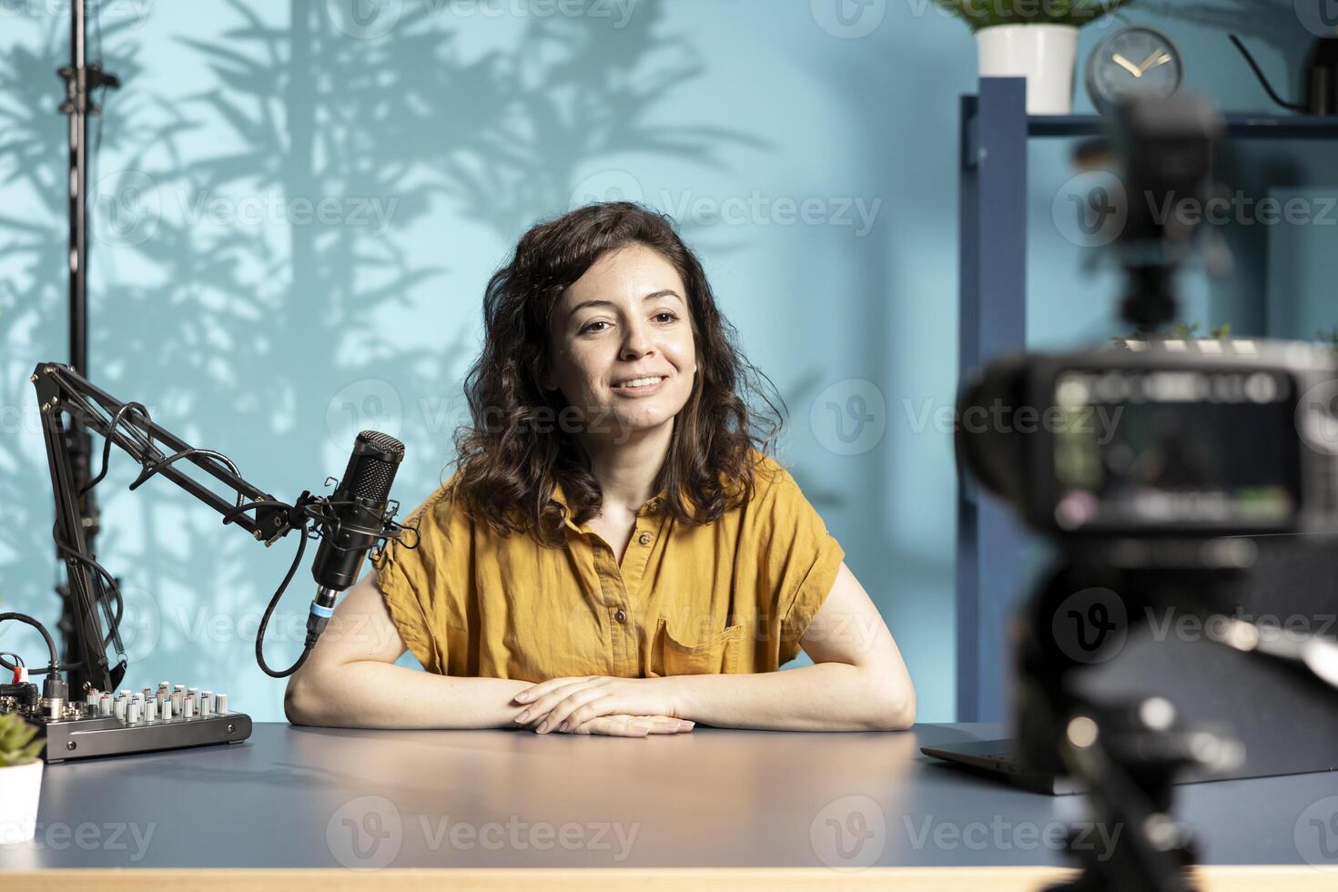 Cheerful content creator using high tech quality mic in studio to do ASMR , discussing with viewers. Smiling woman using professional microphone to record podcast in studio photo