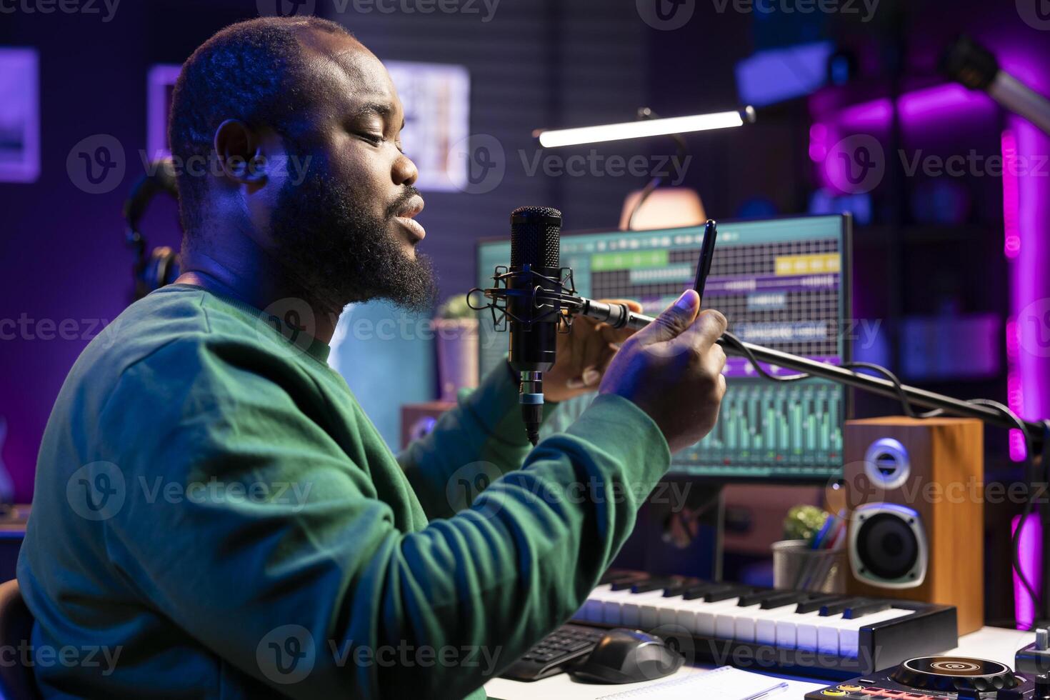 Artist songwriter performing his new musical creation in home studio, recording a new song for the acoustic version launch. Young composer uses phone to read melodic elements and verses. photo