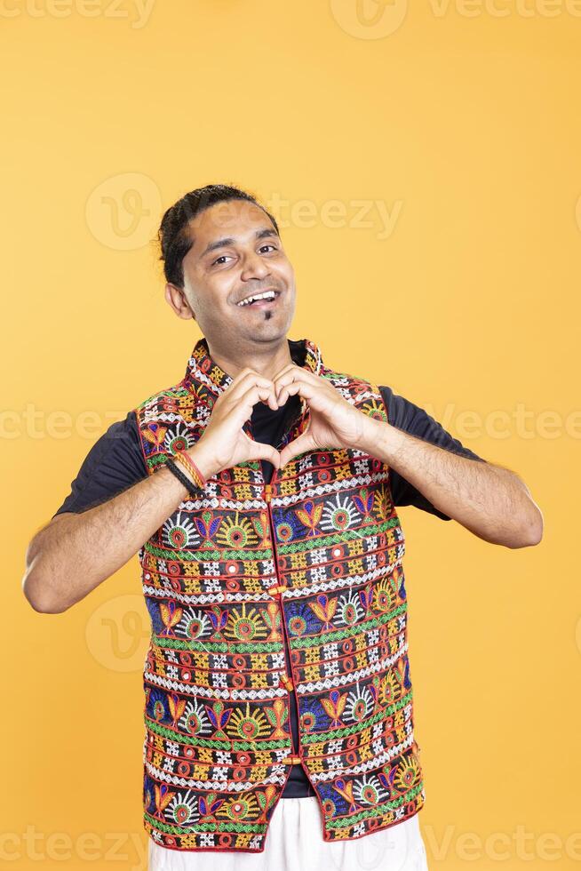 Portrait of happy nice man doing heart symbol shape gesture with hands, showing kindness. Jolly loving person showing love gesturing, being appreciative, isolated over studio backdrop photo
