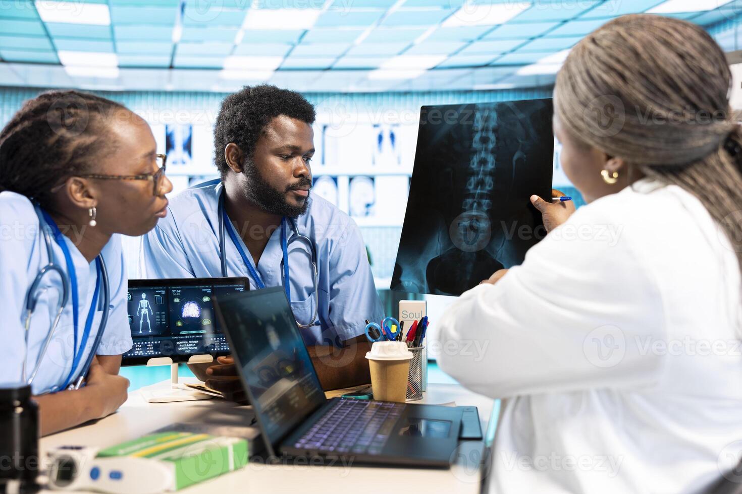 Group of doctor and junior nurses specialists in scrubs analyzing results, emphasizing teamwork and professional training at private clinic. African american medical staff doing research. photo