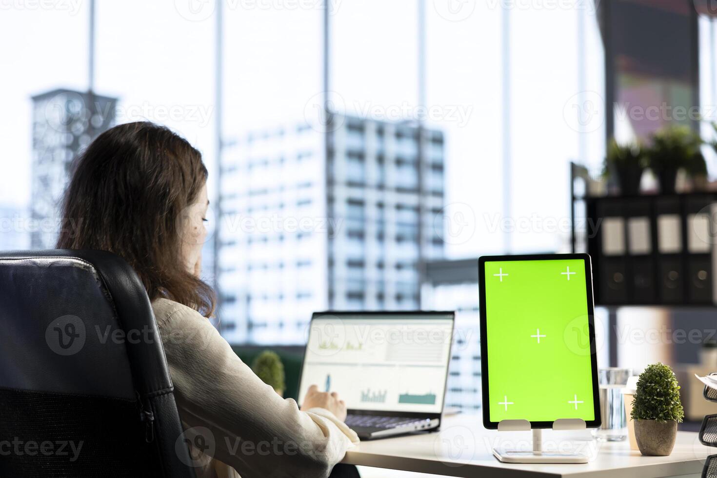 General director working in her own office with green screen, looking at device display and developing a new project idea. Female entrepreneur empowered by corporate culture. photo