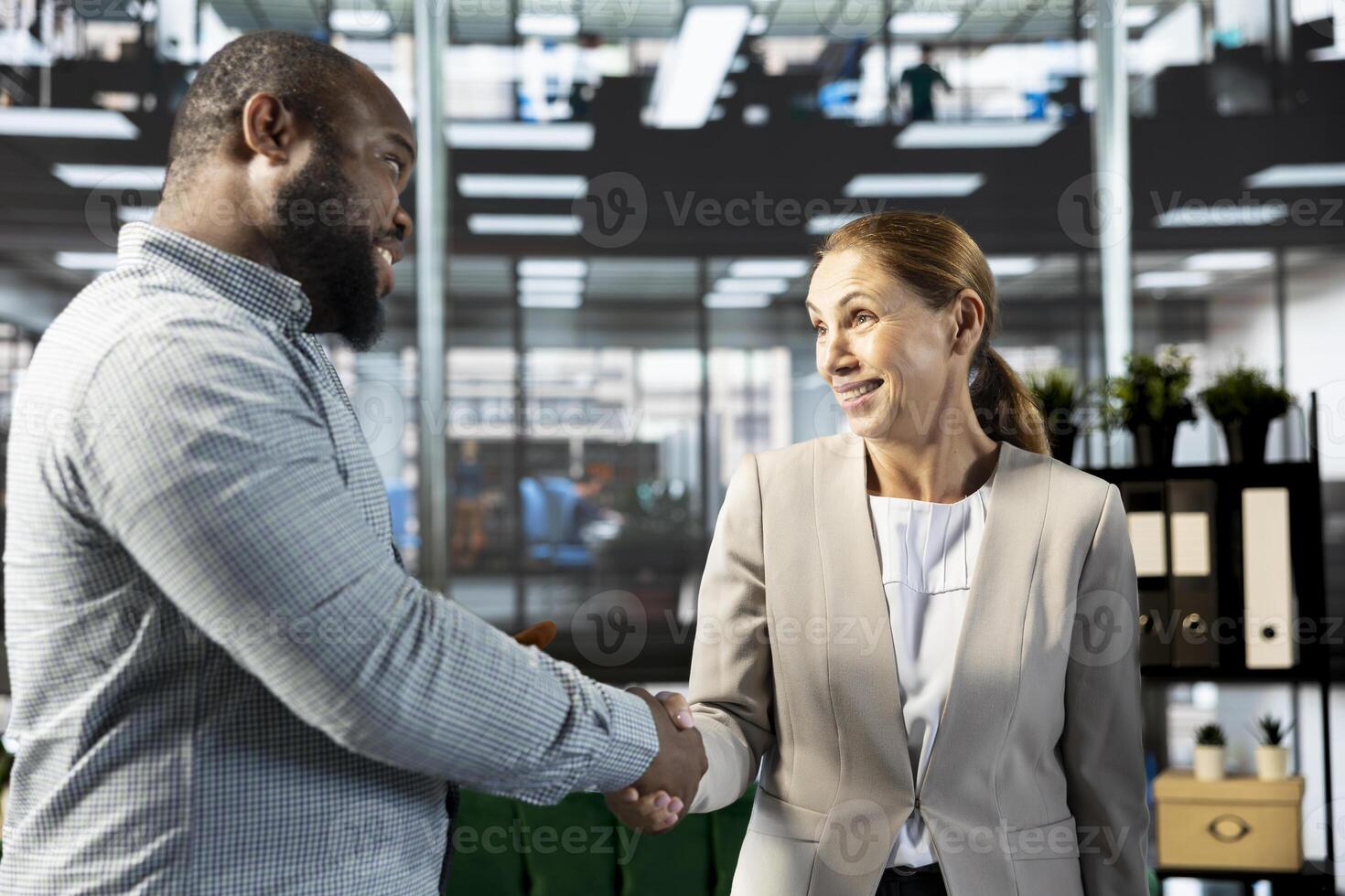 Happy interviewer holding meeting with african american job candidate, doing handshake, asking questions and presenting company background. Cheerful HR worker interviewing man for open position photo