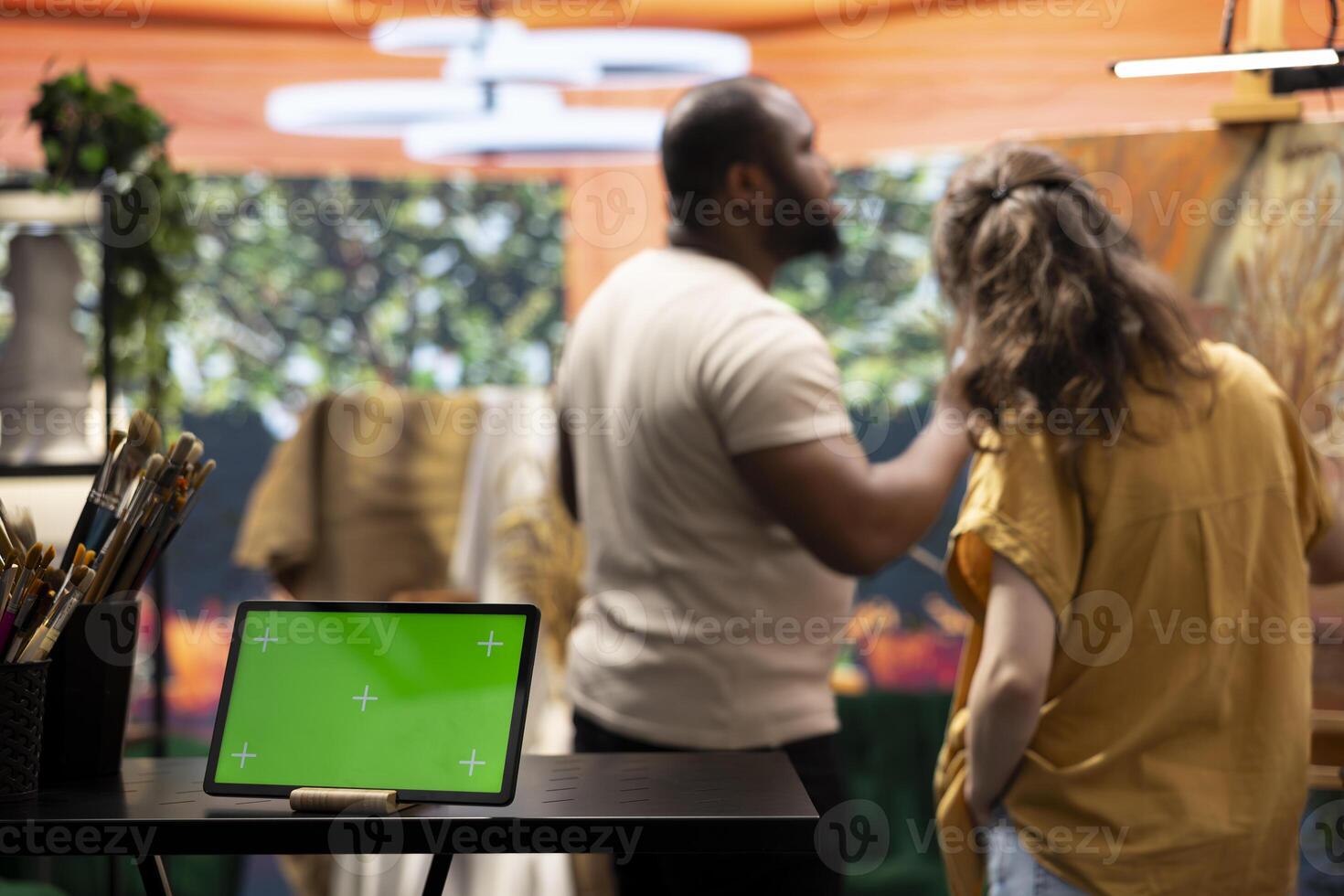 In a creative atelier, painters use colorful paint tubes and brushes to create a masterpiece next to copy space display. Team of artists working on a nature inspired painting. photo
