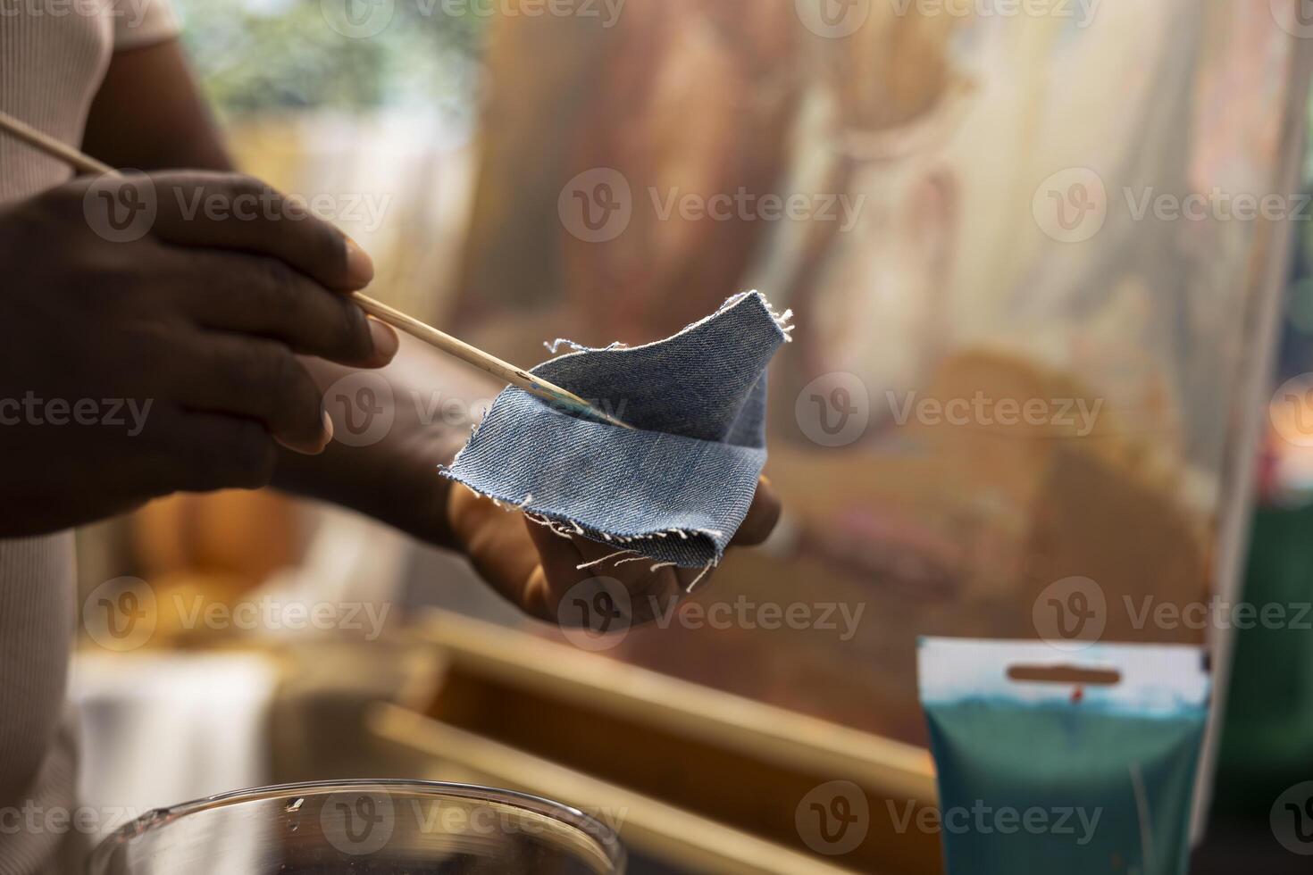Skilled painter wiping the brush on denim fabric to clean the colors, applying a different dye shade on canvas. Talented man working hard on his new artistic painting. Close up. photo