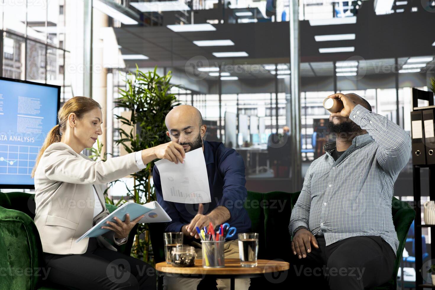 Accountants looking over revenue figures on documents in office. Employees in office focused on comparing company statistical numbers, working hard to finish job before deadline photo