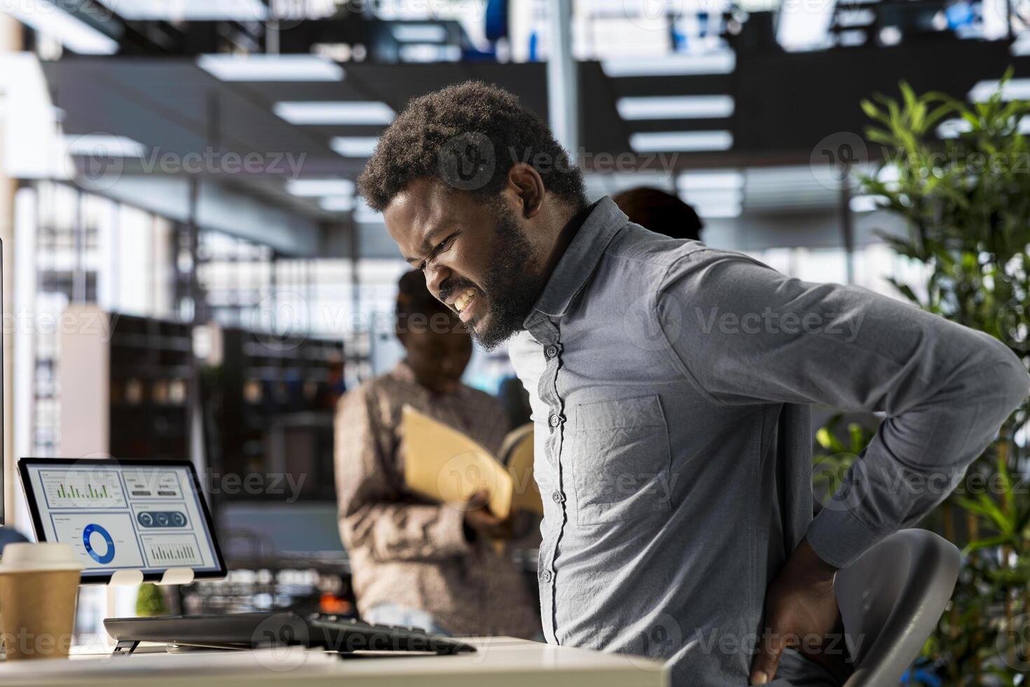 African american business analyst deals with back pain and muscle cramps, improving his incorrect posture at the desk. Suffering from spasms and inflammation due to sedentary life. photo