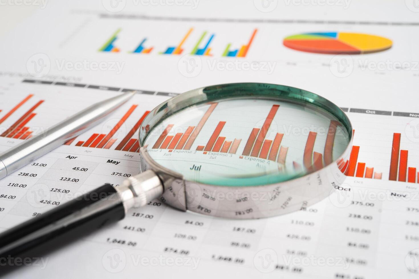 Magnifying glass on spreadsheet and graph paper. Financial photo
