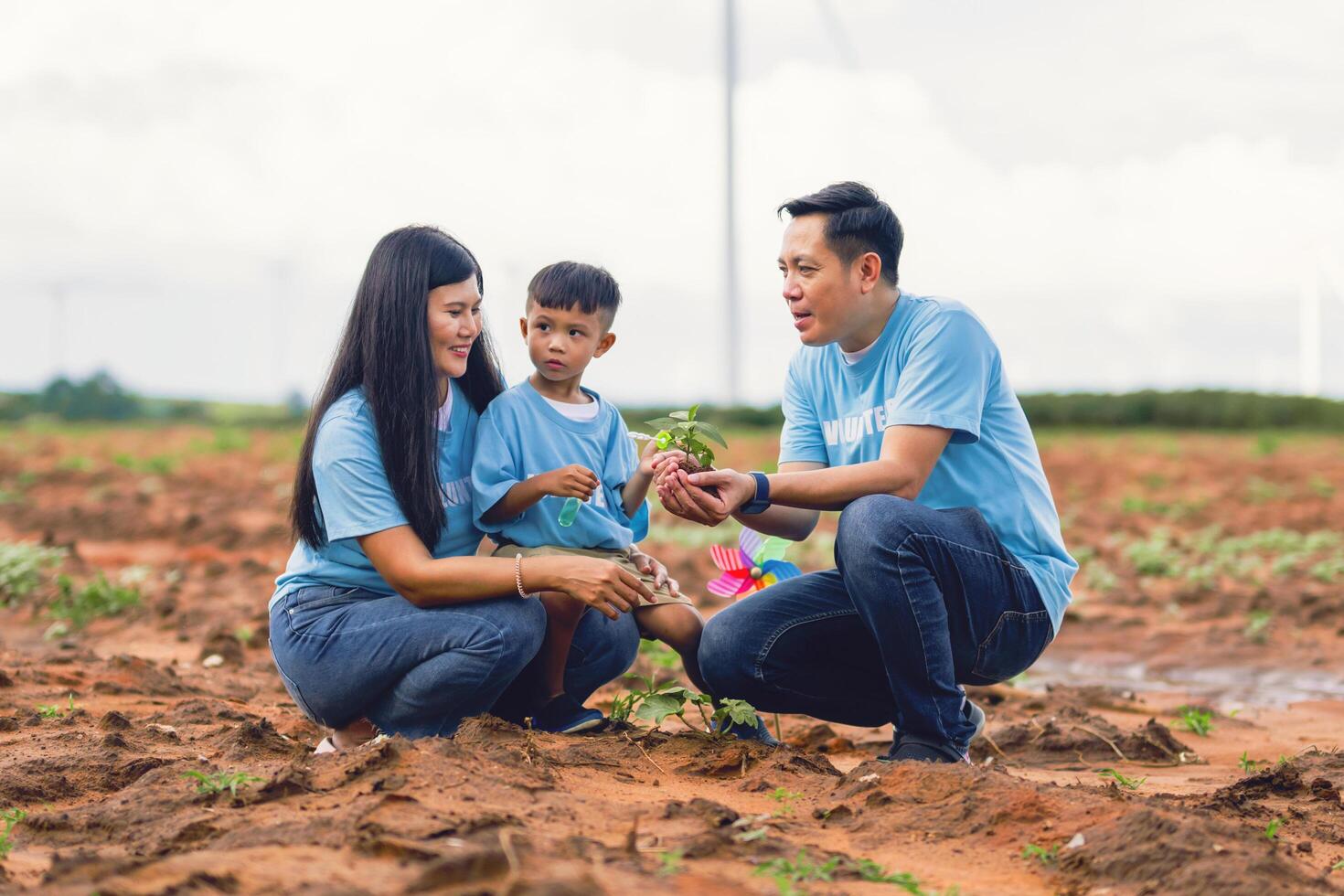 family of three, a man and two children, are planting a tree together photo