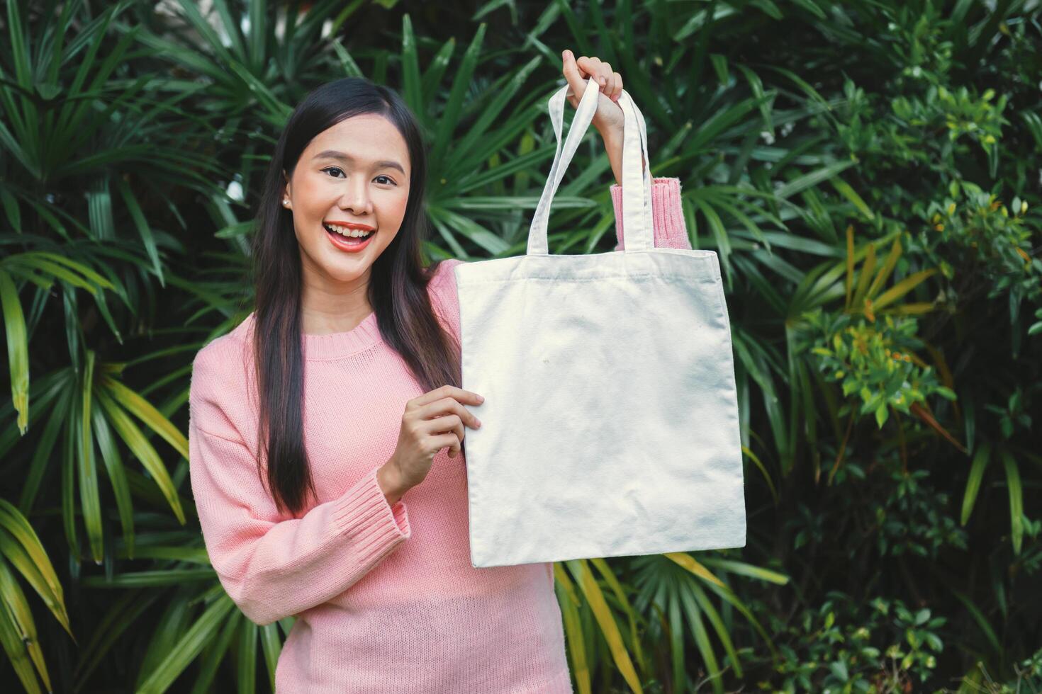 woman is holding a white shopping bag in a lush green environment photo