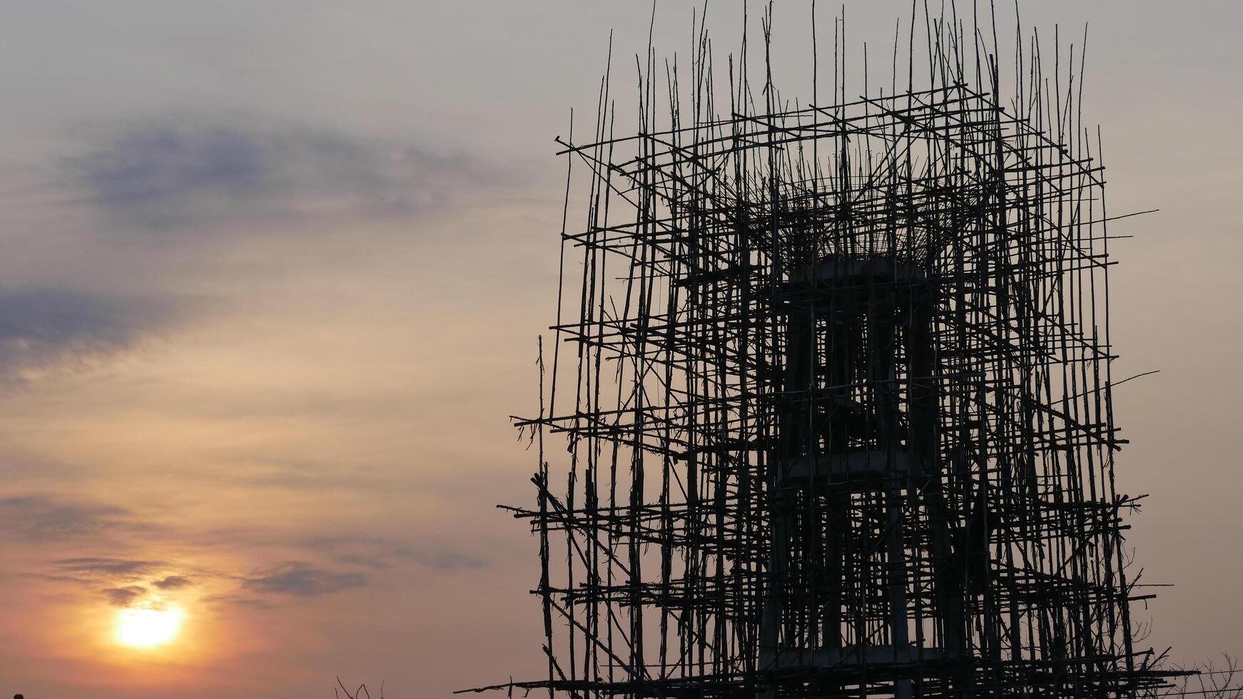 A scaffolding structure silhouetted against sunset sky, showcasing intricate wooden b photo