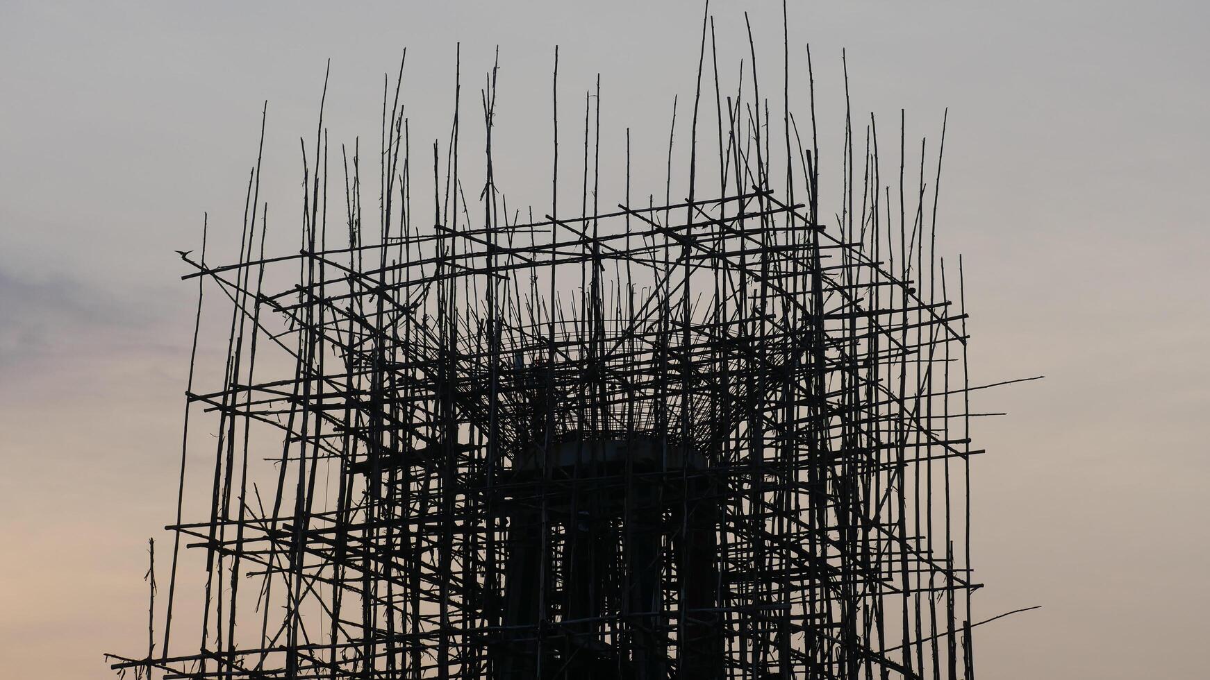 A silhouette of construction site with scaffolding against sunset sky, showcasing intricate structure of framework. scene evokes sense of progress and development photo