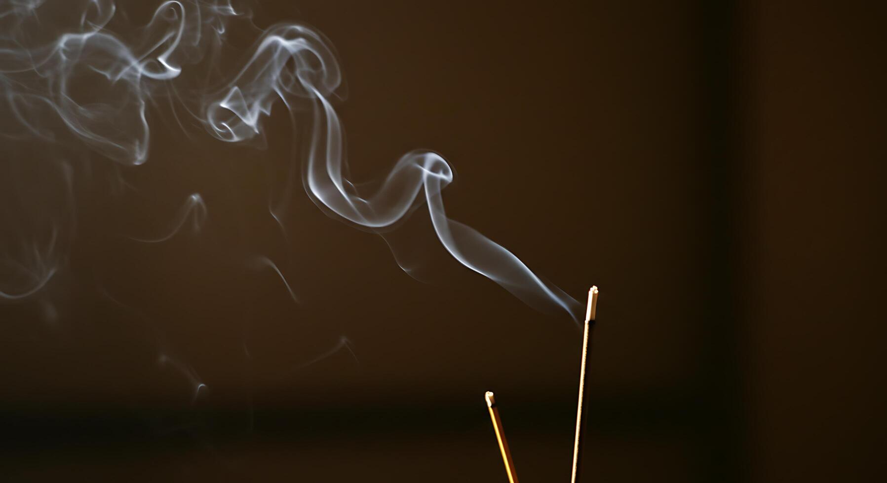 Aromatic Incense Sticks Burning with Delicate Smoke Against Dark Backdrop photo