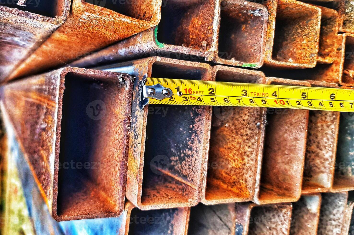 Measuring Rusty Metal Square Tubing with Tape Measure for the Construction photo