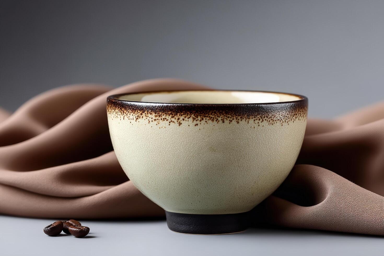 Ceramic tea cup with light glaze displayed on fabric background with coffee beans photo