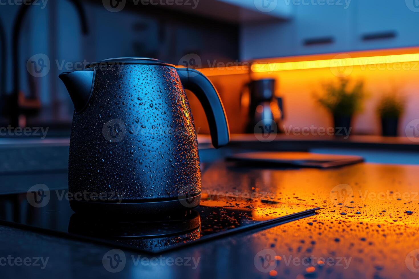 Kettle with droplets reflecting the warm glow of kitchen lights during evening hours photo
