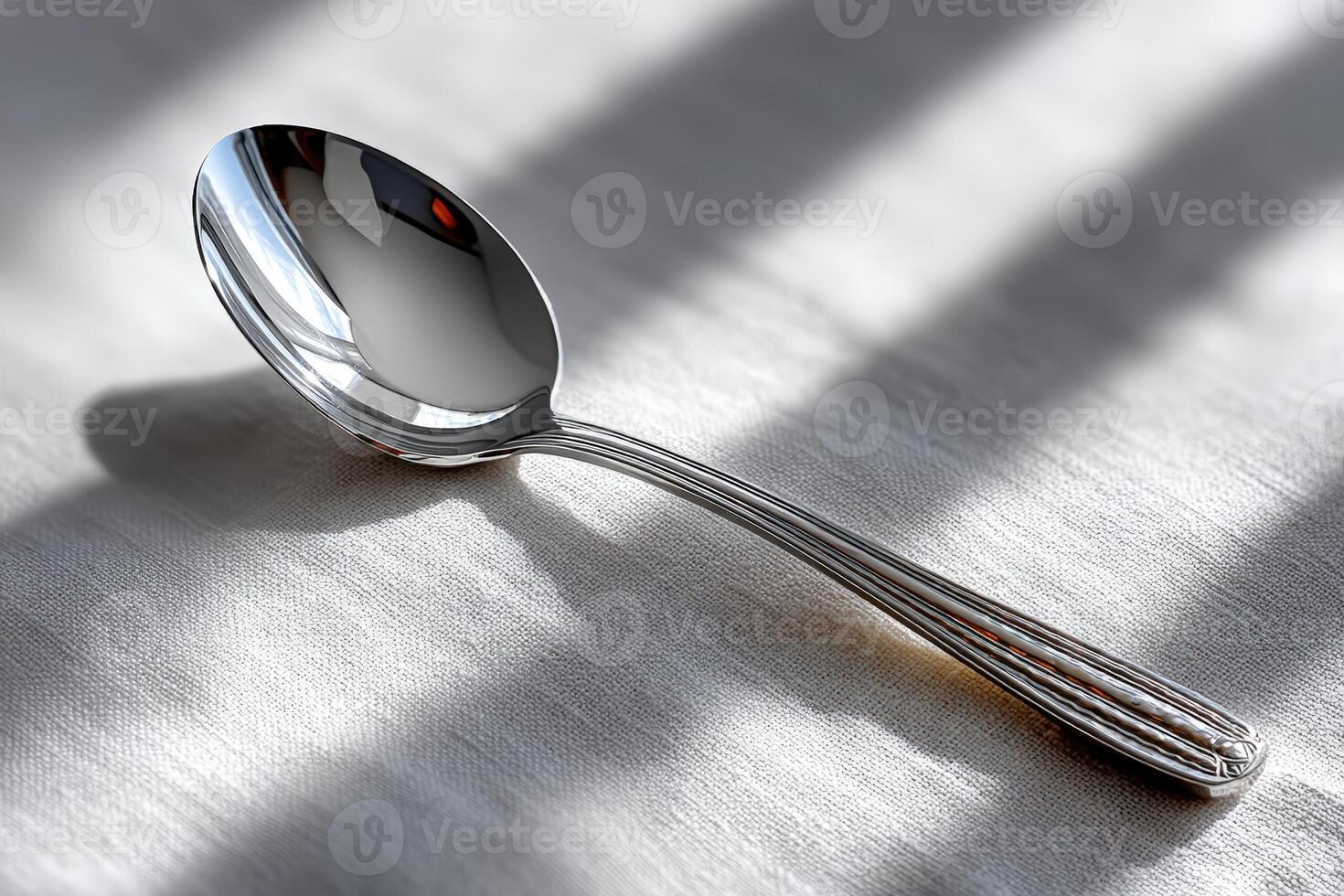 Gleaming silver spoon on a textured white fabric in natural light photo