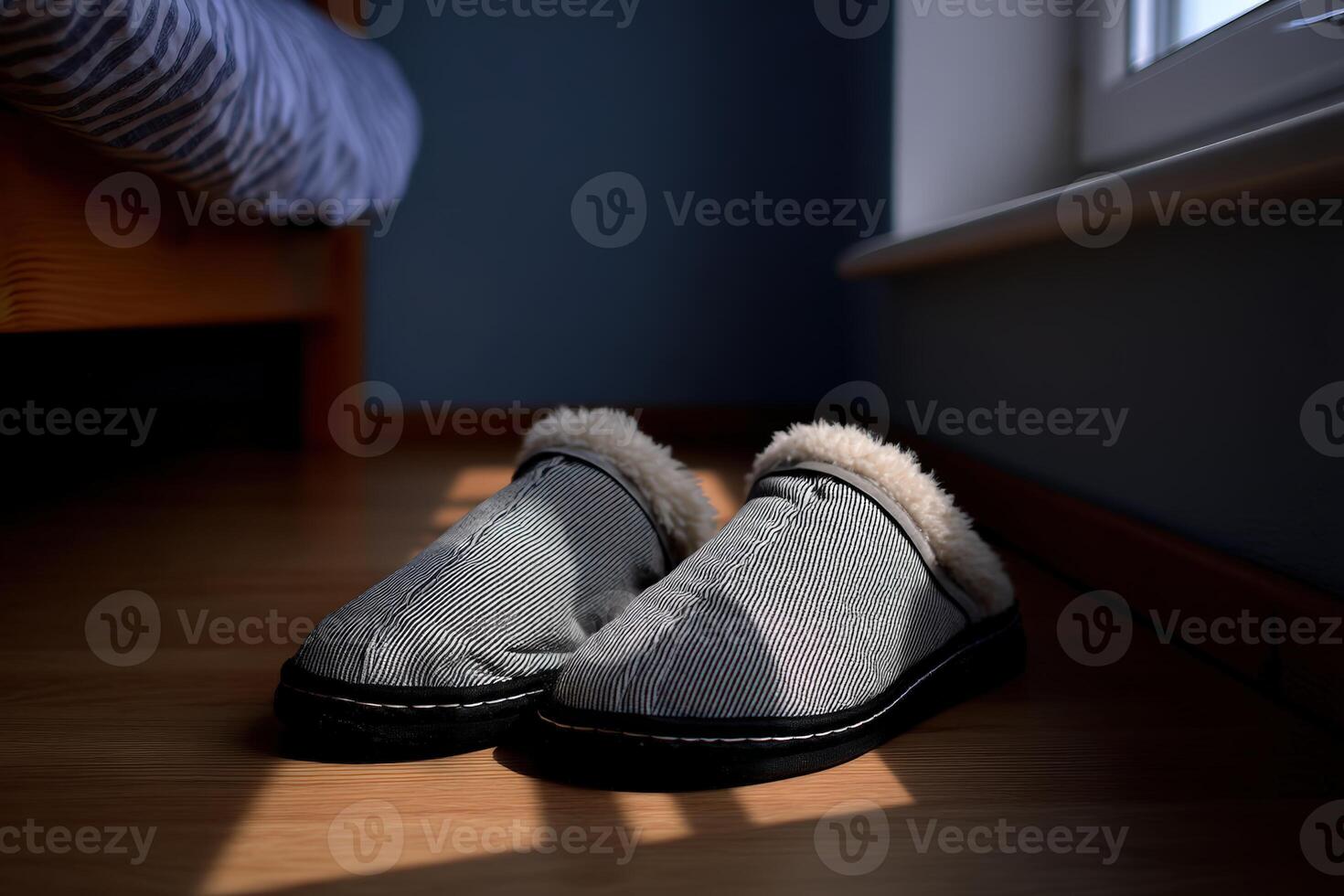 Cozy slippers resting on wooden floor in a softly lit room next to a bed photo