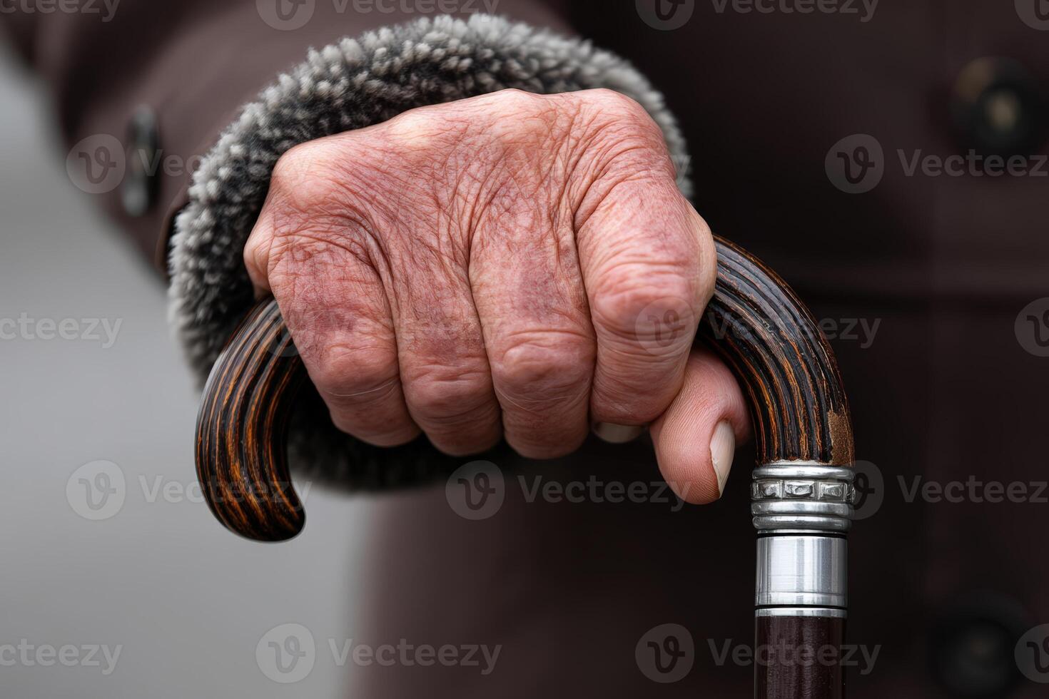 Elderly hand gripping a cane in cool weather while wearing a warm coat photo