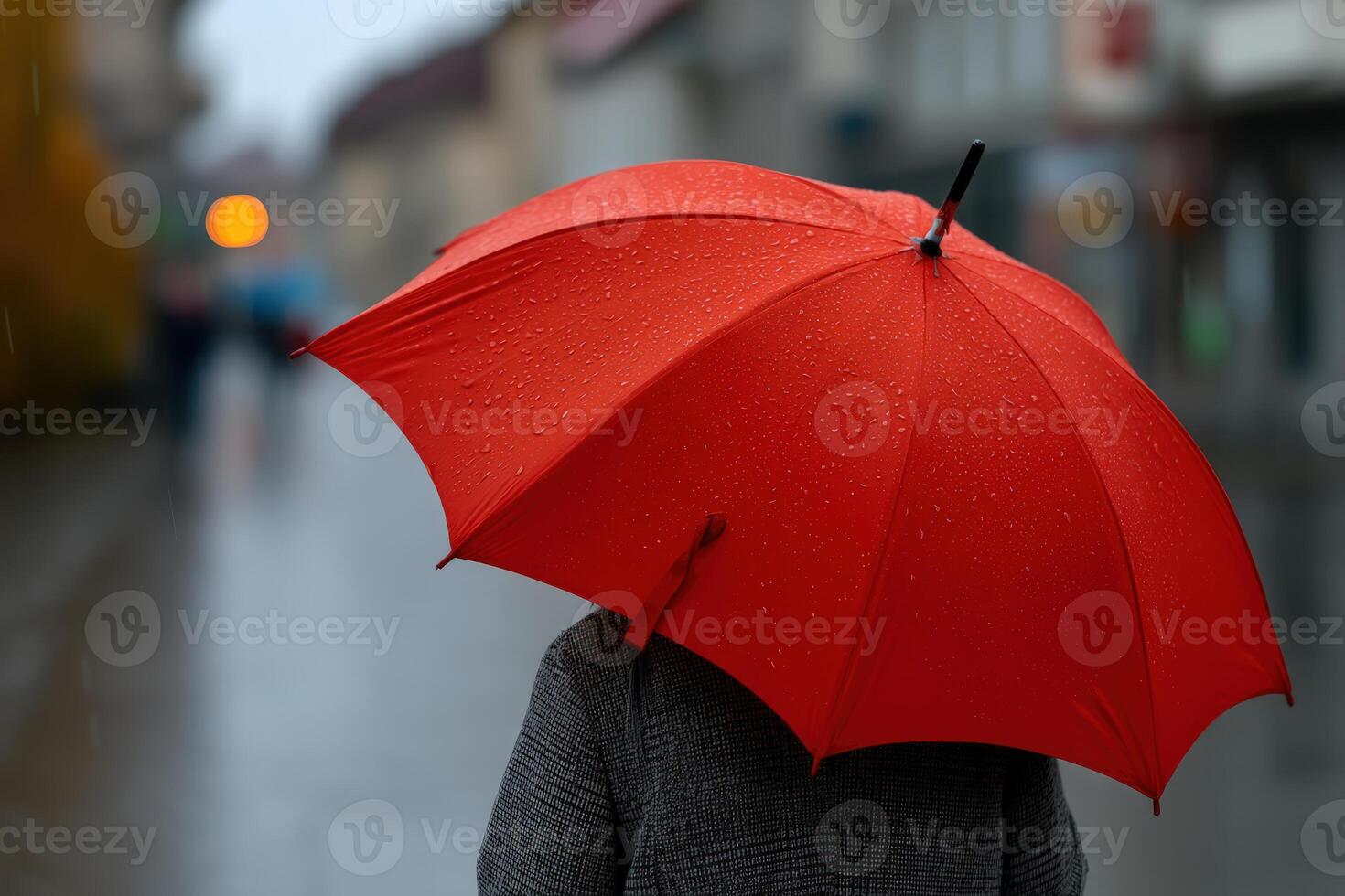 Vibrant red umbrella contrasts with rainy street in urban setting during gloomy weather photo