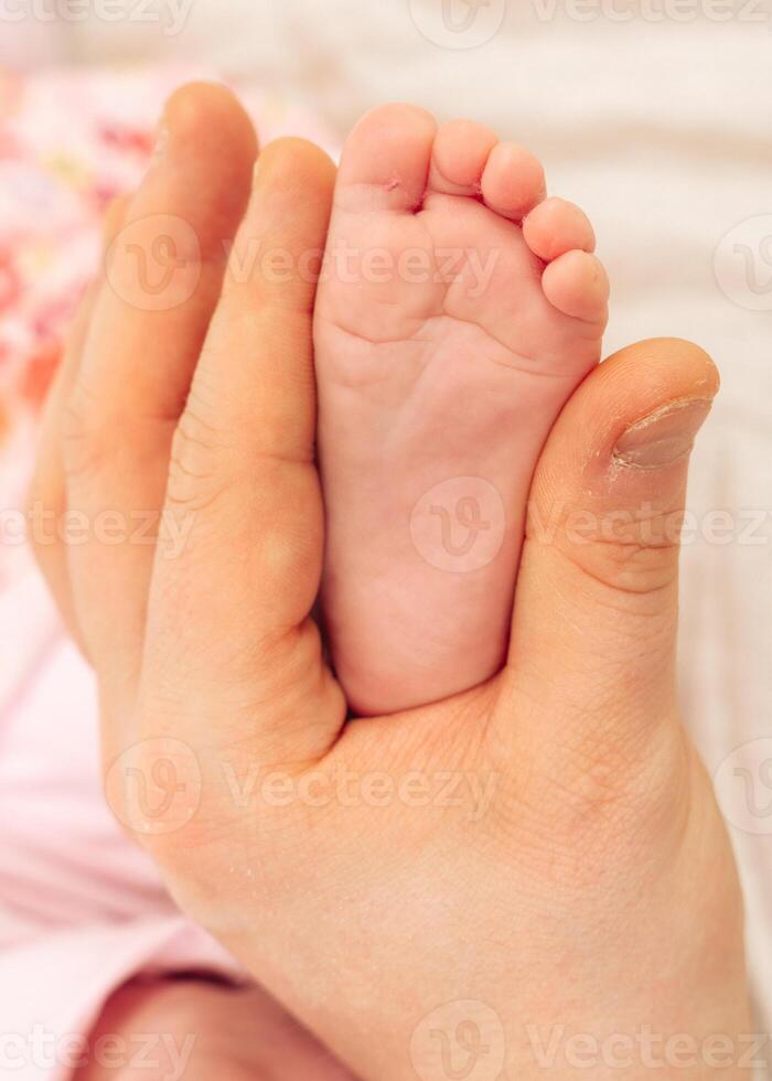 Close-up of an adults hand gently holding a tiny newborn baby foot, symbolizing tenderness, protection, and unconditional love between parent and child. A touching and emotional moment. photo