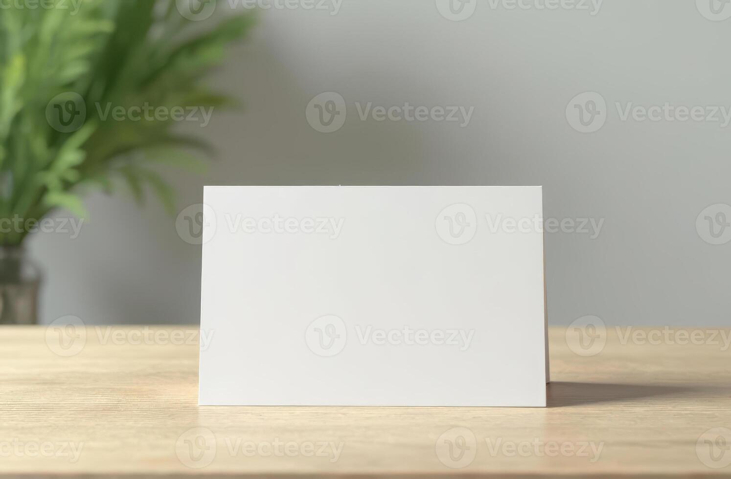 Blank greeting card on wooden table with greenery in soft natural light, minimalist scene photo