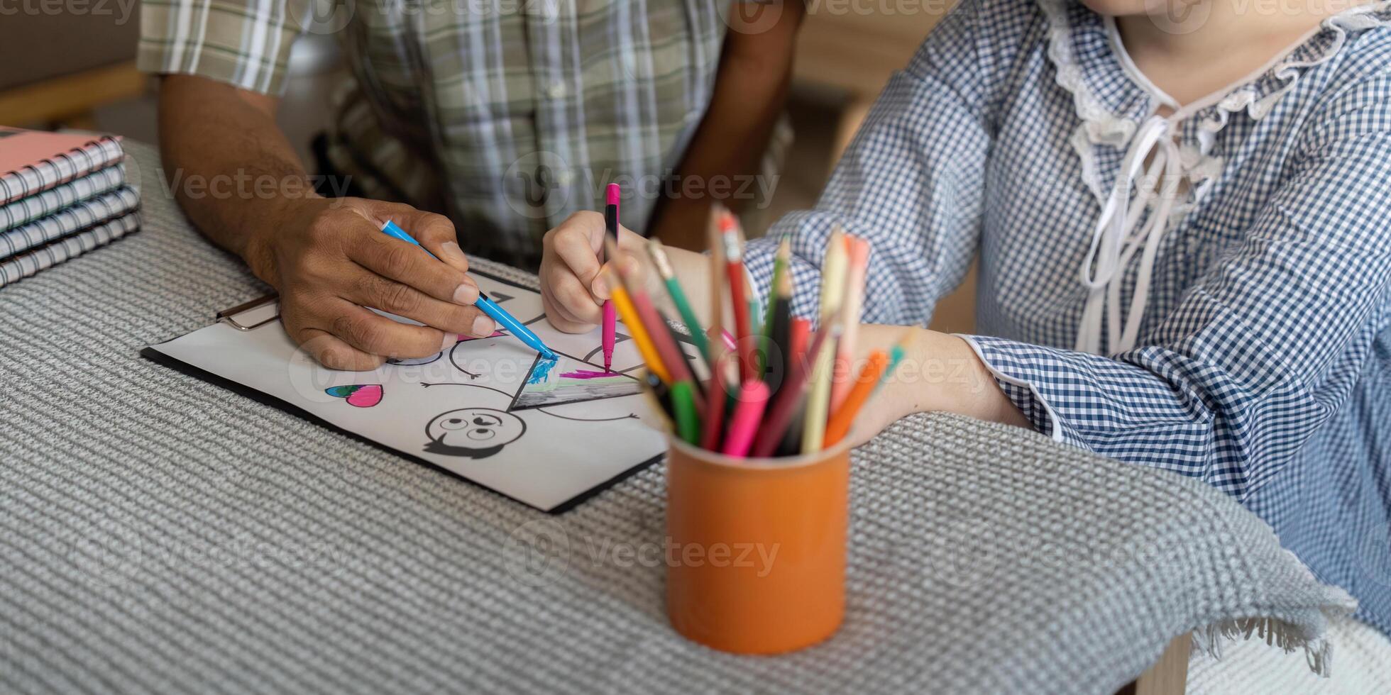 Creative Learning and Support. A caregiver assists a teenage girl with Down syndrome in her drawing activity. photo