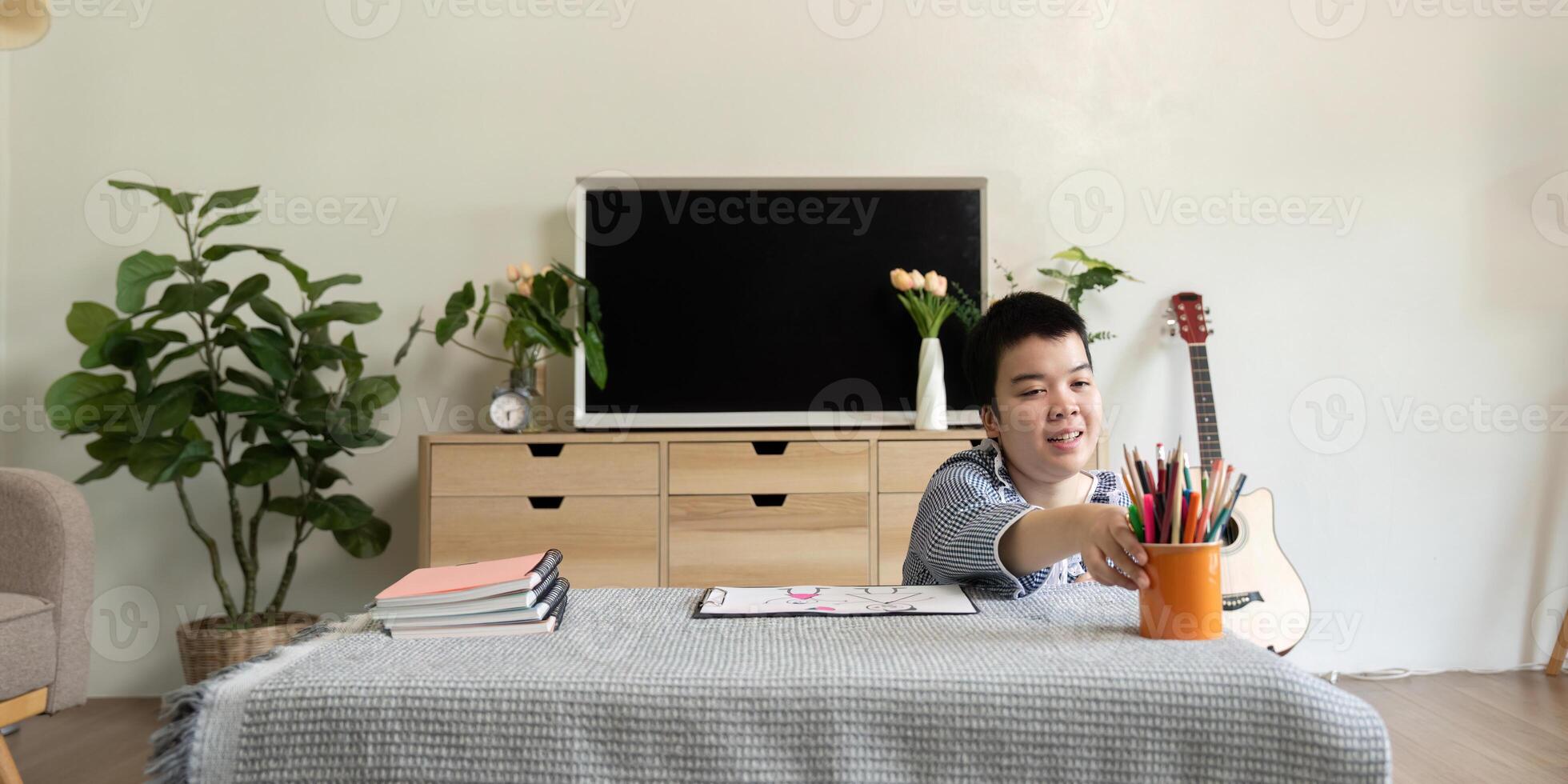 Artistic Expression and Learning. A teenage girl with Down syndrome reaching for art supplies at home. photo