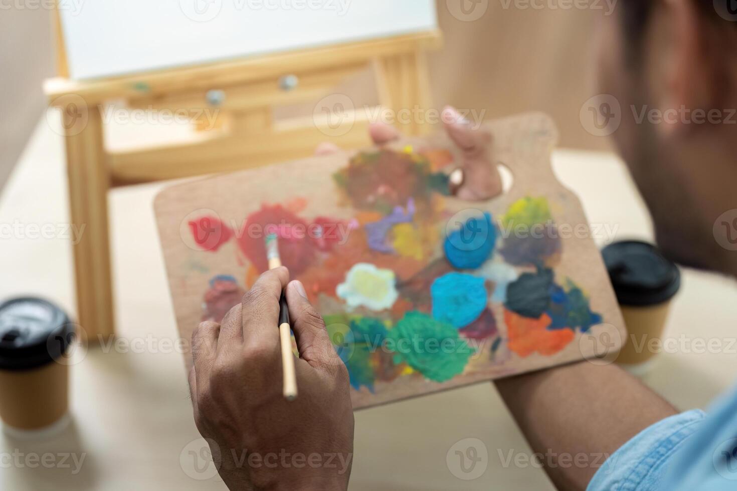 Gay couple painting together with colorful palette at home photo
