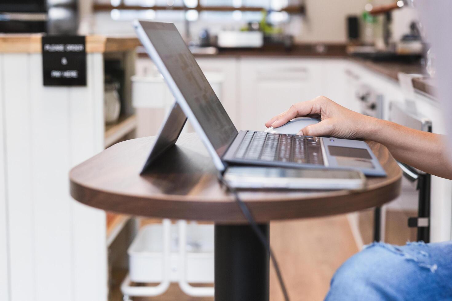 Focus on woman hand holding computer mouse while working on laptop. photo