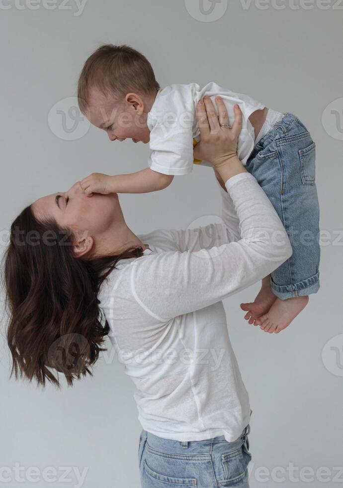 Mom holds her son in her arms, and he covers her face with his hands photo