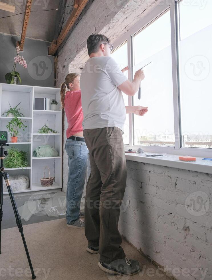 a young couple toning windows glass at home using toning film photo
