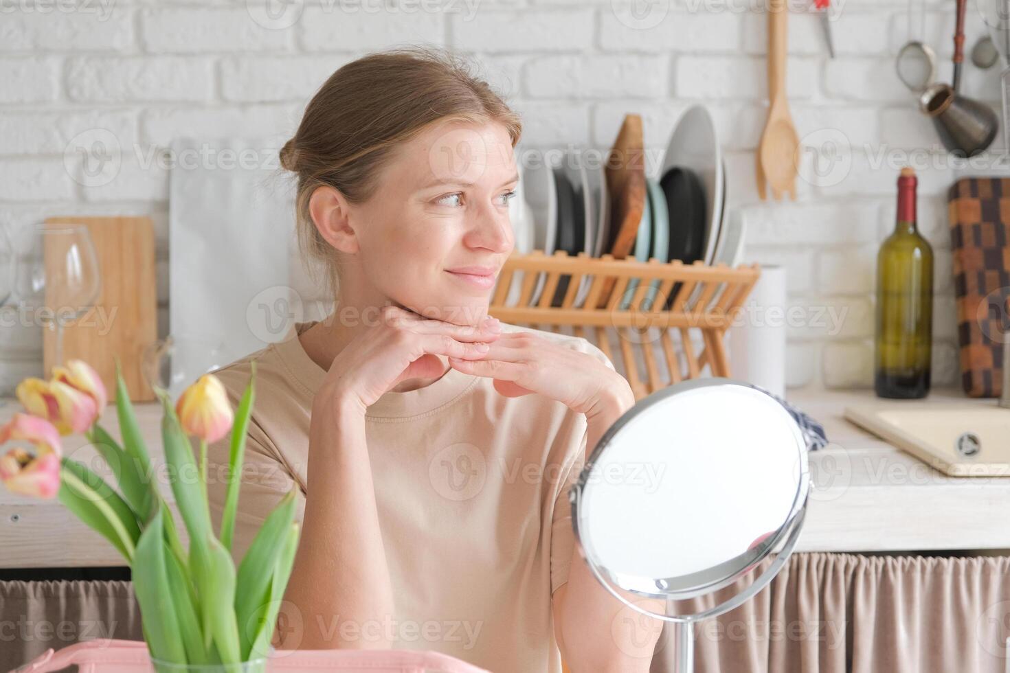 woman applying makeup in the kitchen in the morning photo