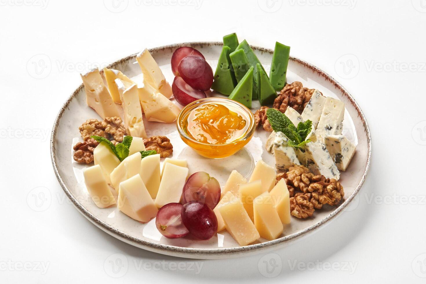 Plate of gourmet cheeses with walnuts, grapes and orange jam photo