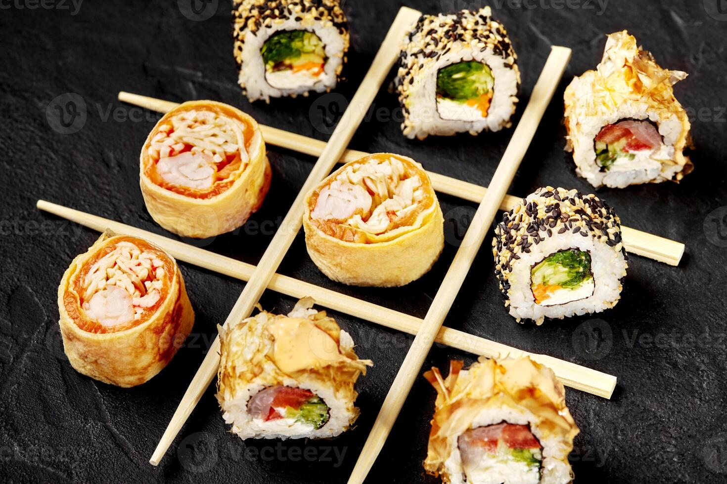 Sushi rolls forming a tic-tac-toe game on a black background photo