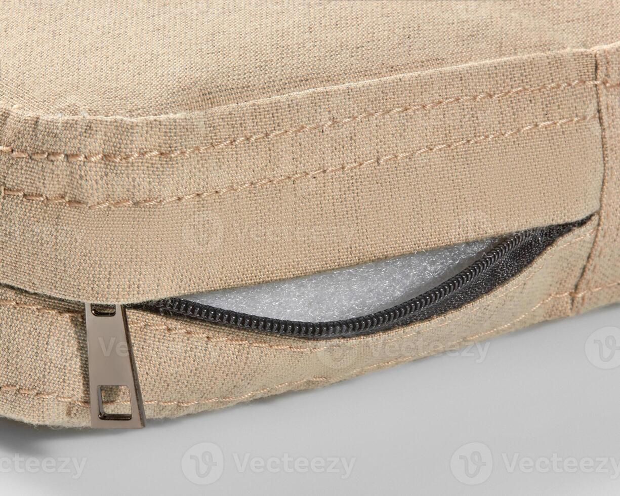 Open zipper showing foam filling of beige fabric cushion photo