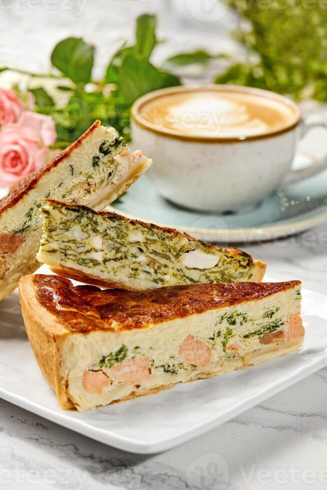 Delicious homemade quiche with salmon and spinach filling enjoyed with cappuccino photo