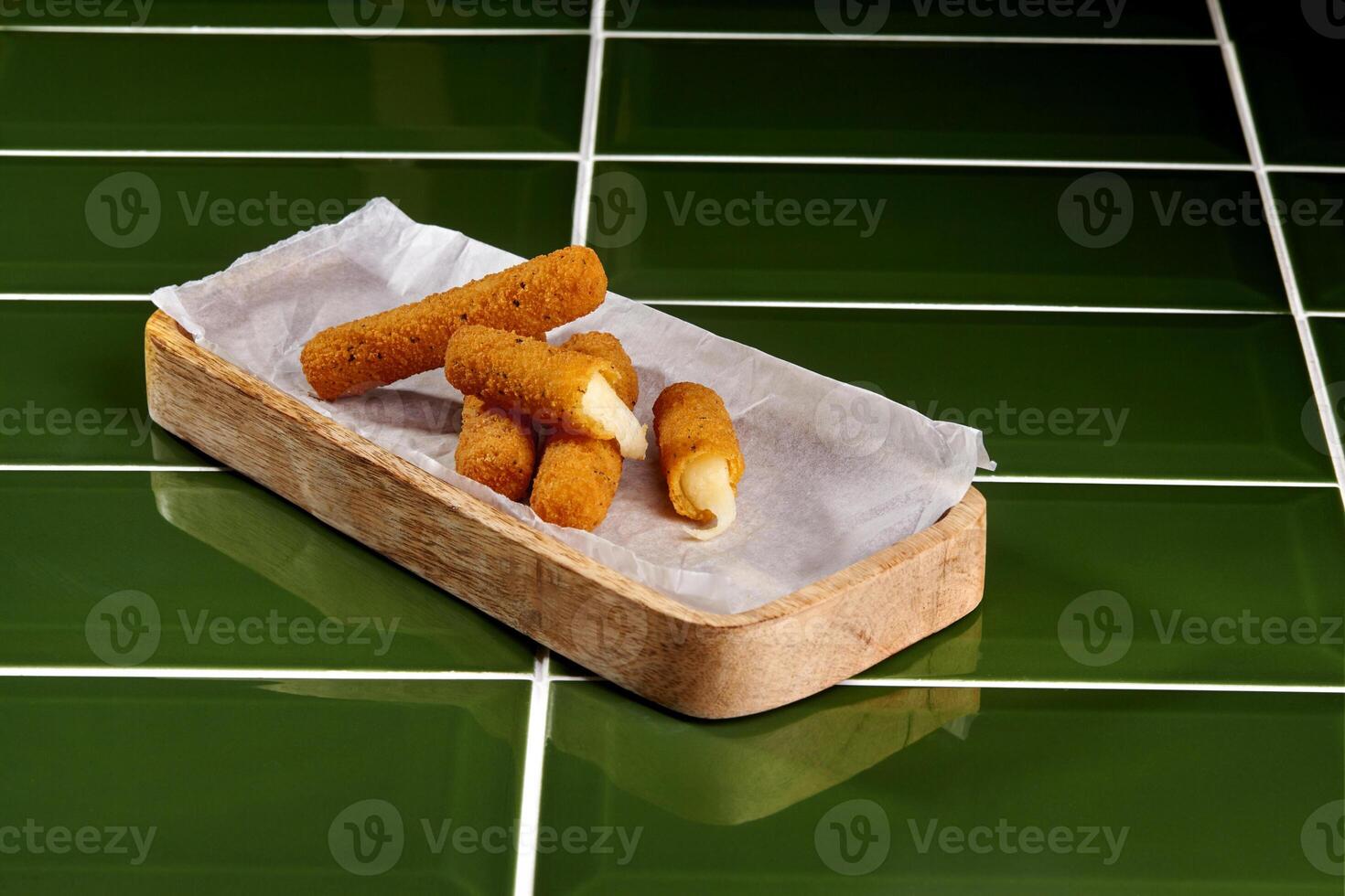 Breaded mozzarella sticks with marinara dipping sauce on green tiles photo