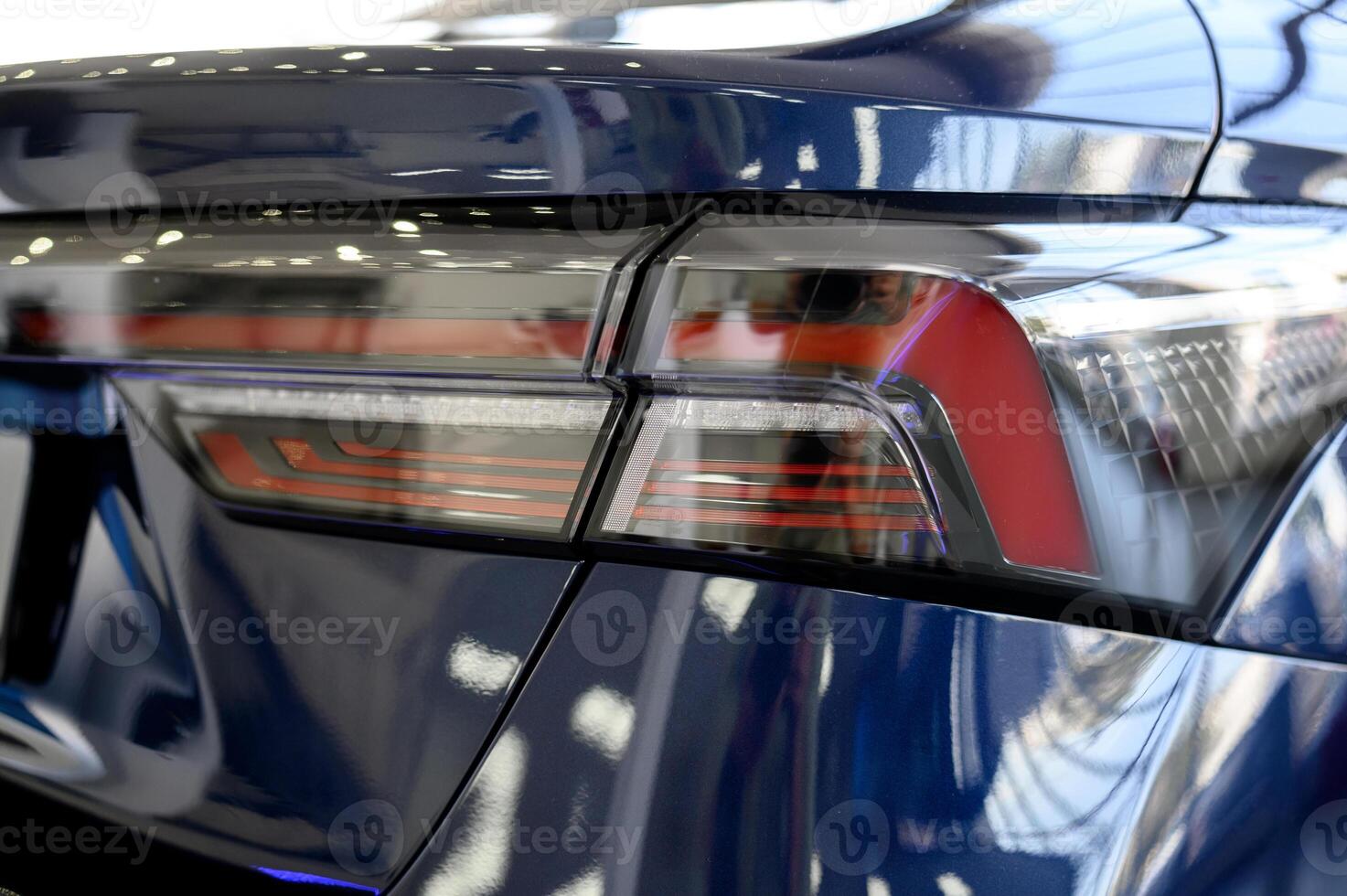 The rear lights of a blue car are reflected in the glass photo