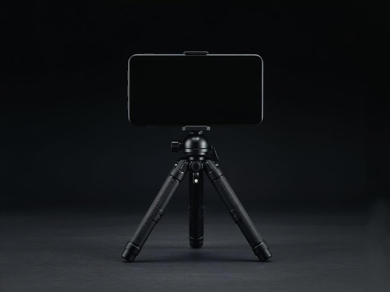 A sleek black smartphone mounted on a compact tripod against a dark minimalist background setup shot photo