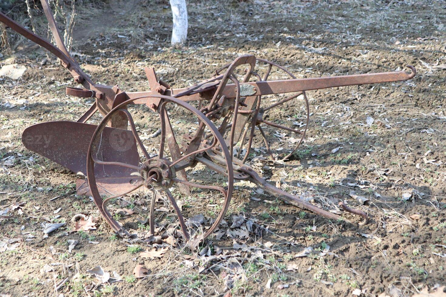 A Rusty Antique Plow Set Against the Backdrop of Beautiful Nature and Scenic Landscapes photo