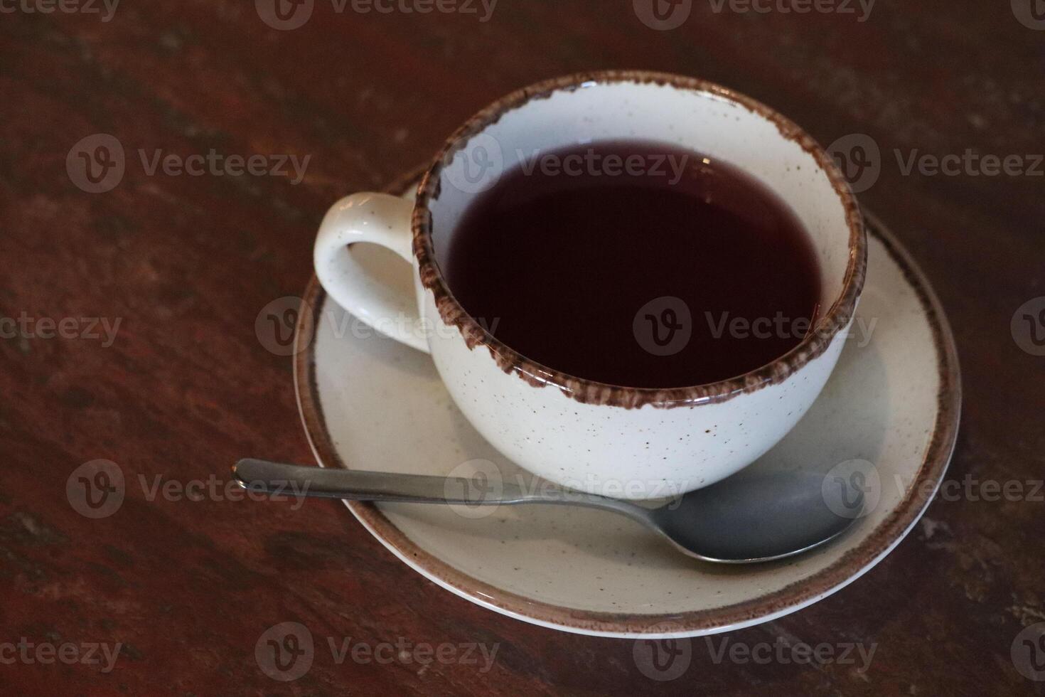 A warm, cozy cup of soothing herbal tea with a delectable chocolate rim on a lovely wooden table photo