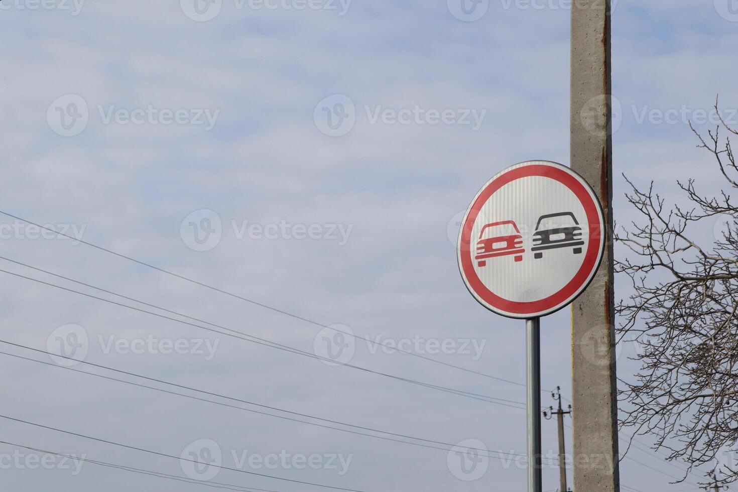 A no overtaking traffic sign is clearly visible beneath a cloudy sky, warning motorists effectively photo