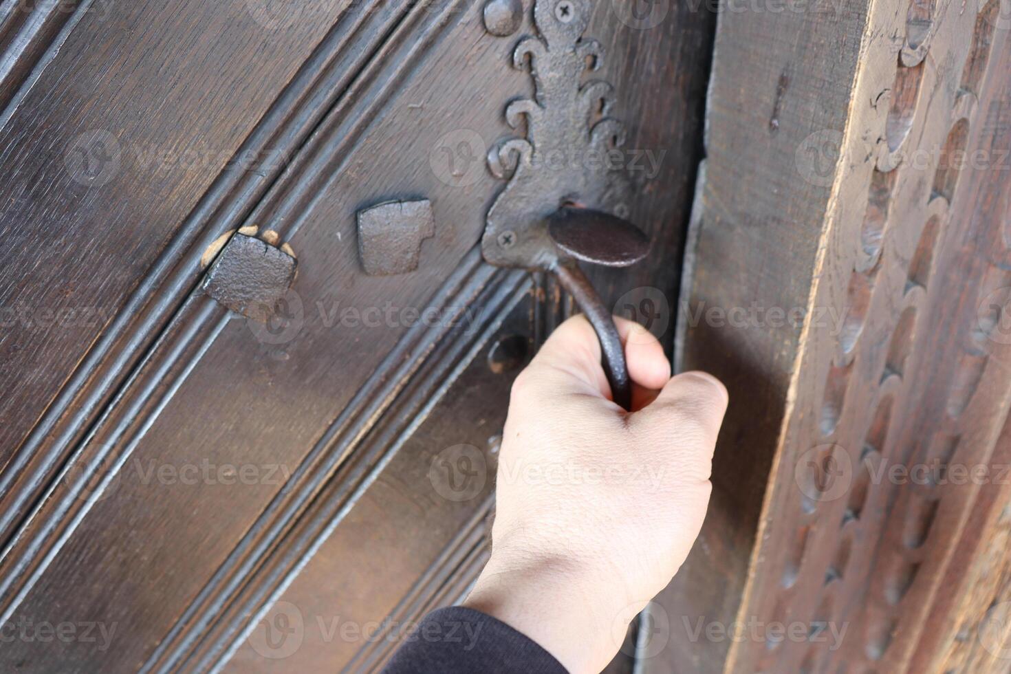 A hand gently reaching out for an intricately designed ornate door handle on a beautiful entrance photo