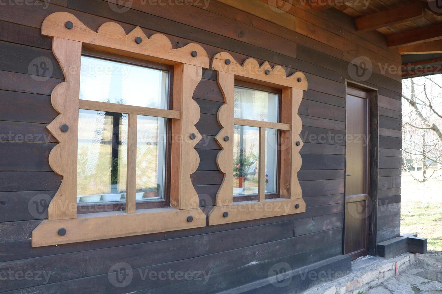 Charming Rustic Wooden Cabin Featuring Beautifully Ornate Window Frames and Details photo