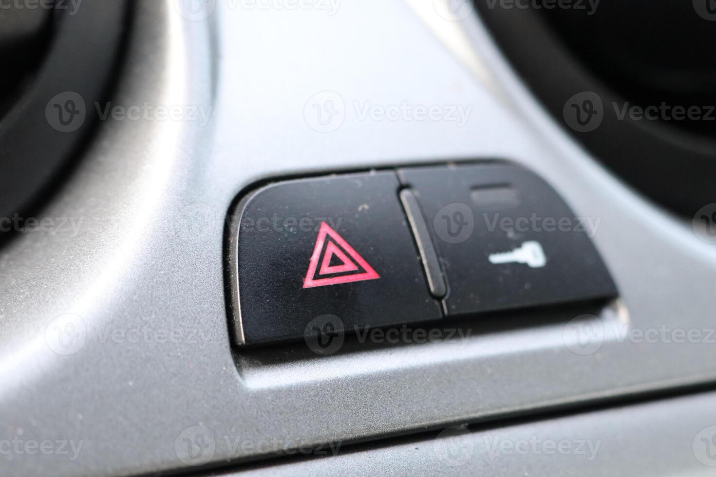 This specific button is designed to activate the emergency alert signal on a cars dashboard photo