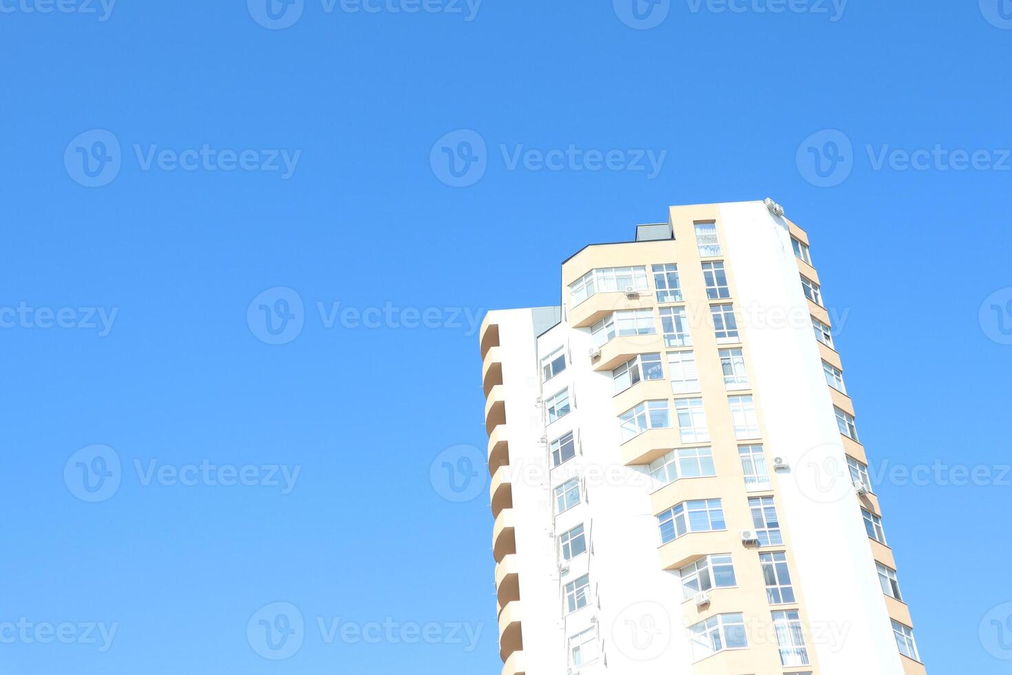 A contemporary modern highrise building prominently set against a clear, bright blue sky photo
